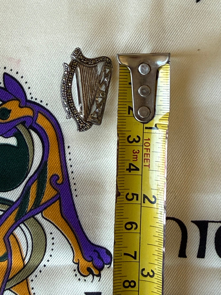 Vintage Solvar harp brooch photographed beside measuring tape