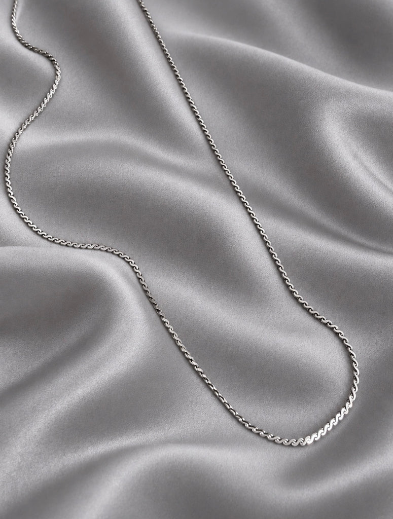 Vintage Mexican silver necklace arranged on soft satin fabric