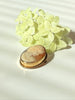 Angled view of vintage carved shell cameo showing textured gold-filled border