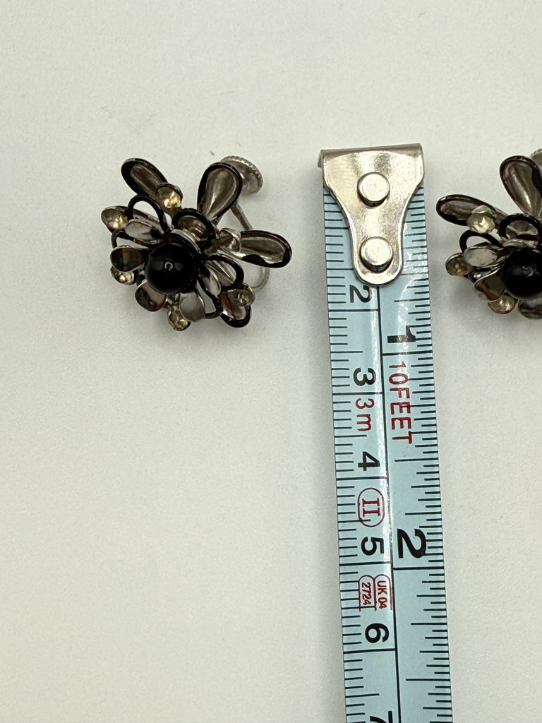 Vintage black flower earring beside measuring tape showing approximately 2 cm height
