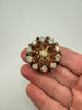 Vintage rhinestone starburst brooch shown in hand highlighting layered dimensional design