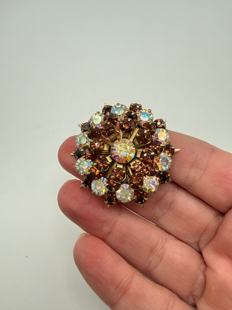 Vintage rhinestone starburst brooch shown in hand highlighting layered dimensional design