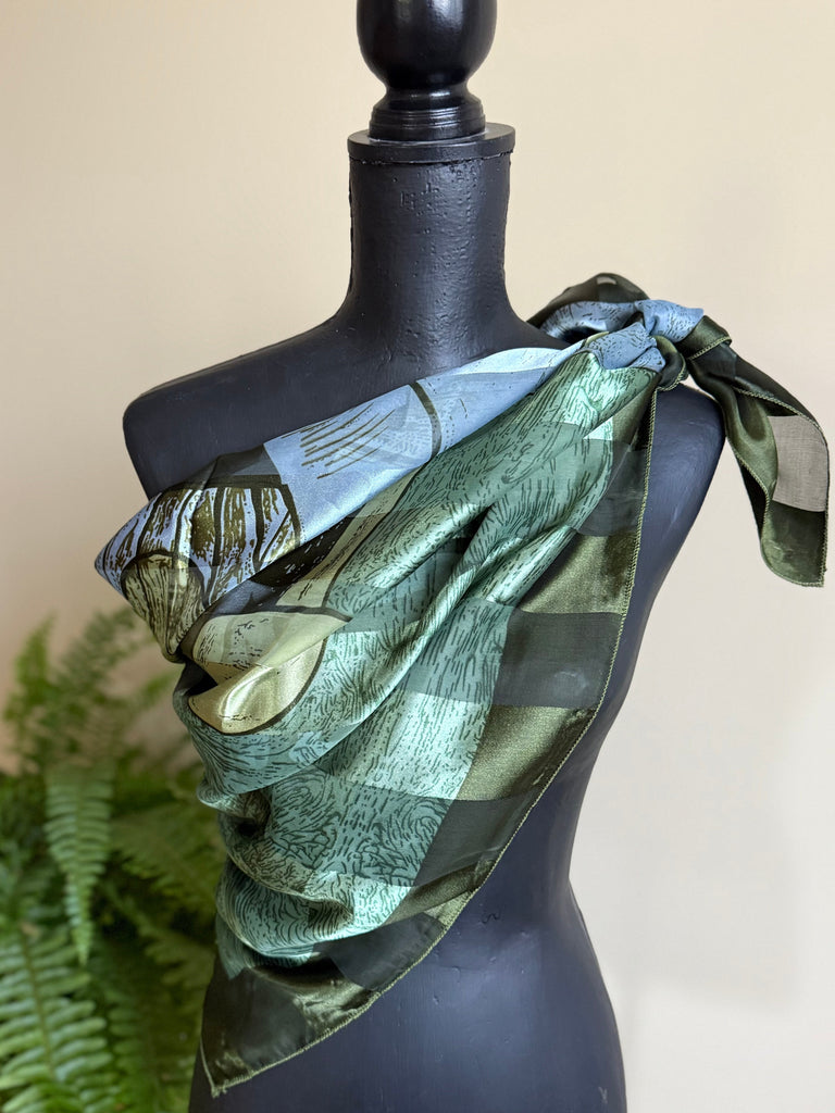 Large green Picasso art scarf styled around the shoulders on mannequin. 
