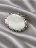 Close-up of vintage Mexican silver oval brooch pendant showing iridescent inlay