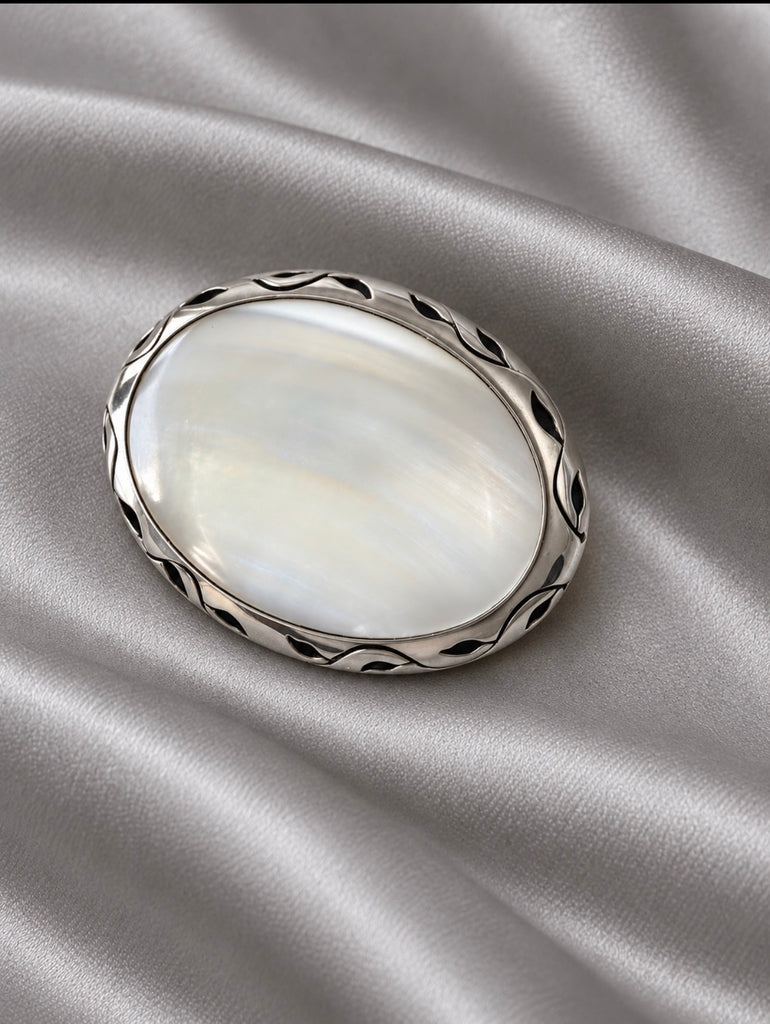 Close-up of vintage Mexican silver oval brooch pendant showing iridescent inlay