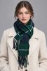 Woman wearing green and navy Scottish tartan lambswool scarf with cream coat