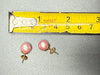 Vintage pink faux pearl stud earrings beside measuring tape showing approximately 10 mm diameter