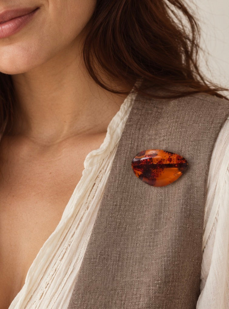 Vintage cognac amber brooch worn on a light-coloured jacket lapel