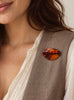 Vintage cognac amber brooch worn on a light-coloured jacket lapel
