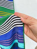 Close-up of colourful striped scarf pattern with green rolled edge. 
