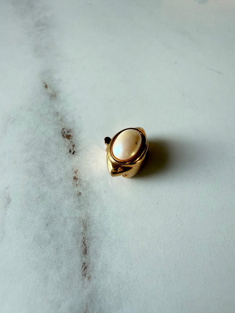 Front view of vintage gold-tone clasp with oval cream faux pearl