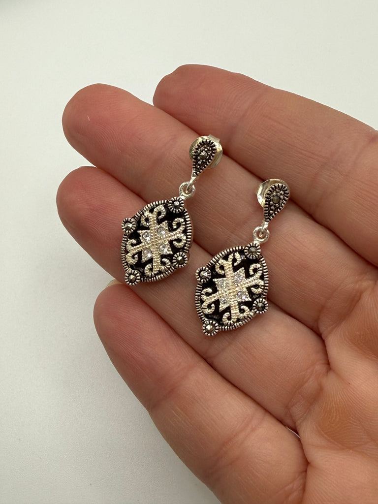 Pair of vintage silver drop earrings with black and clear stones shown in hand for scale