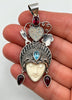 Vintage goddess pendant shown in hand with carved cream face, heart crown and colourful gemstones