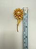 Vintage gold tone flower brooch beside measuring tape showing approximately 6.5 inch length