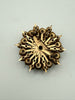 Back of vintage starburst brooch showing textured gold-tone metal and pin closure