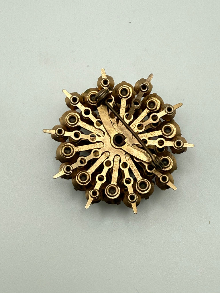 Back of vintage starburst brooch showing textured gold-tone metal and pin closure