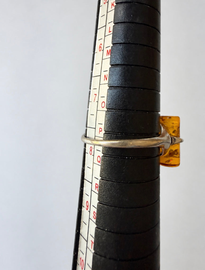 Baltic amber ring displayed beside sizing mandrel showing approximate size 7.5