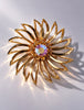 Sarah Coventry gold-tone sunburst flower brooch with iridescent AB crystal centre