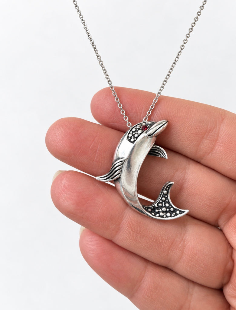 Sterling silver dolphin pendant held in hand showing scale and detail