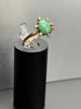 Vintage 14K gold green jade cabochon ring with round diamond halo displayed on black stand