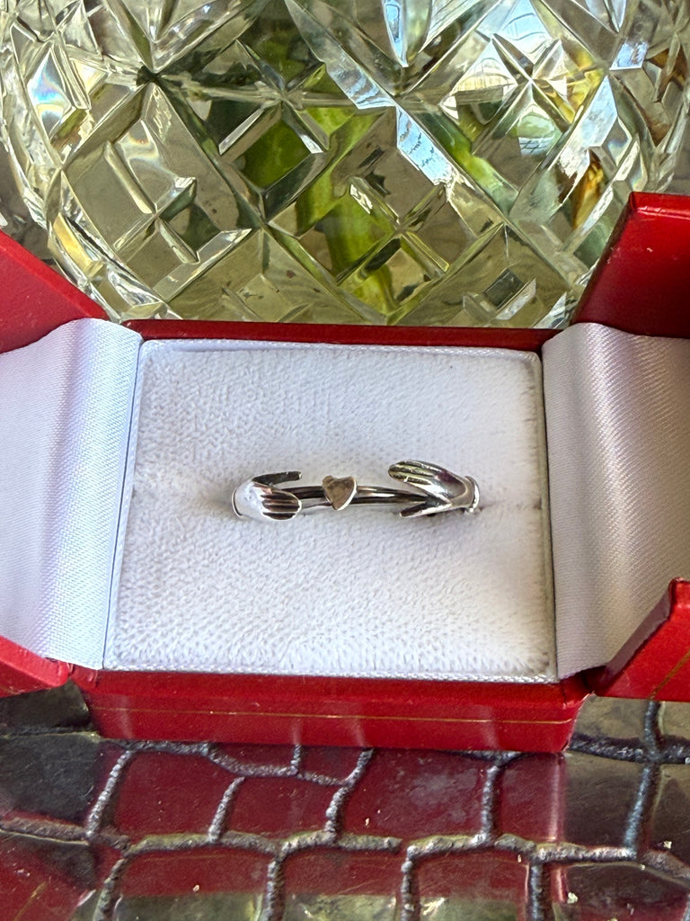 Three-band clasped hands ring displayed in open presentation box