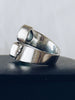 Side view of Sajen silver ring showing ornate scrollwork and blue-green gemstones