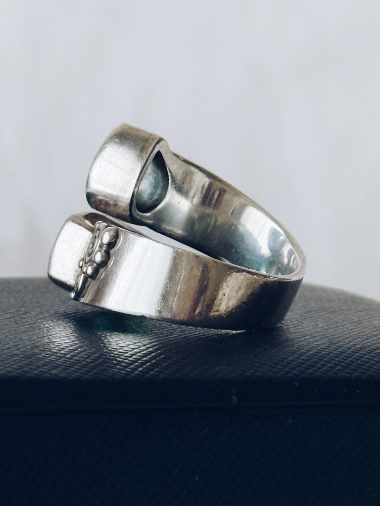 Side view of Sajen silver ring showing ornate scrollwork and blue-green gemstones