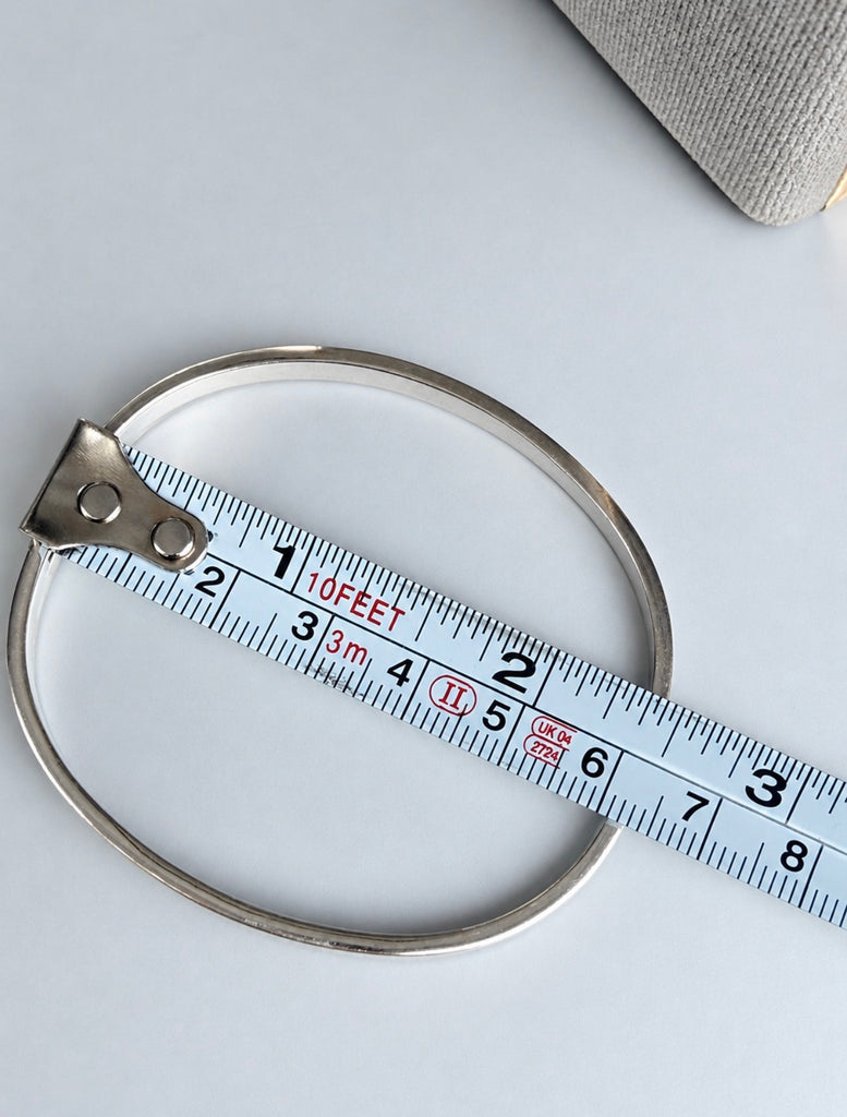 Vintage Mexican silver bangle beside measuring tape showing length