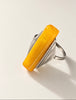 Angled view of geometric 875 silver ring with long opaque yellow amber stone