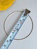 Sterling silver bangle bracelet shown beside measuring tape for size