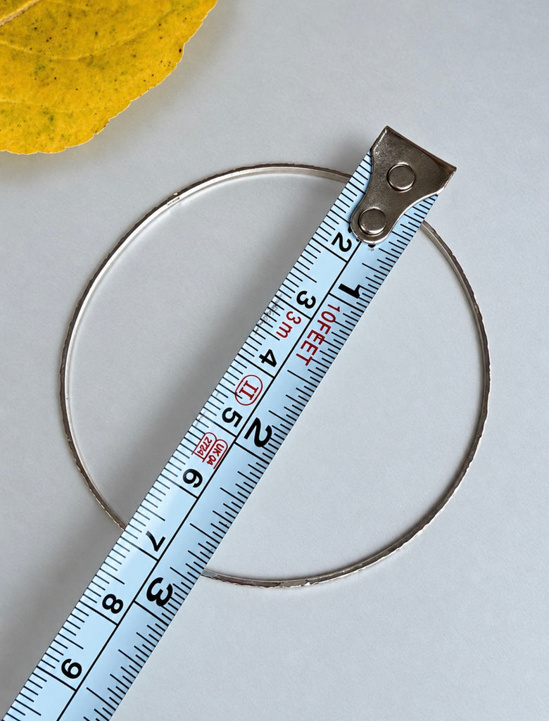 Sterling silver bangle bracelet shown beside measuring tape for size