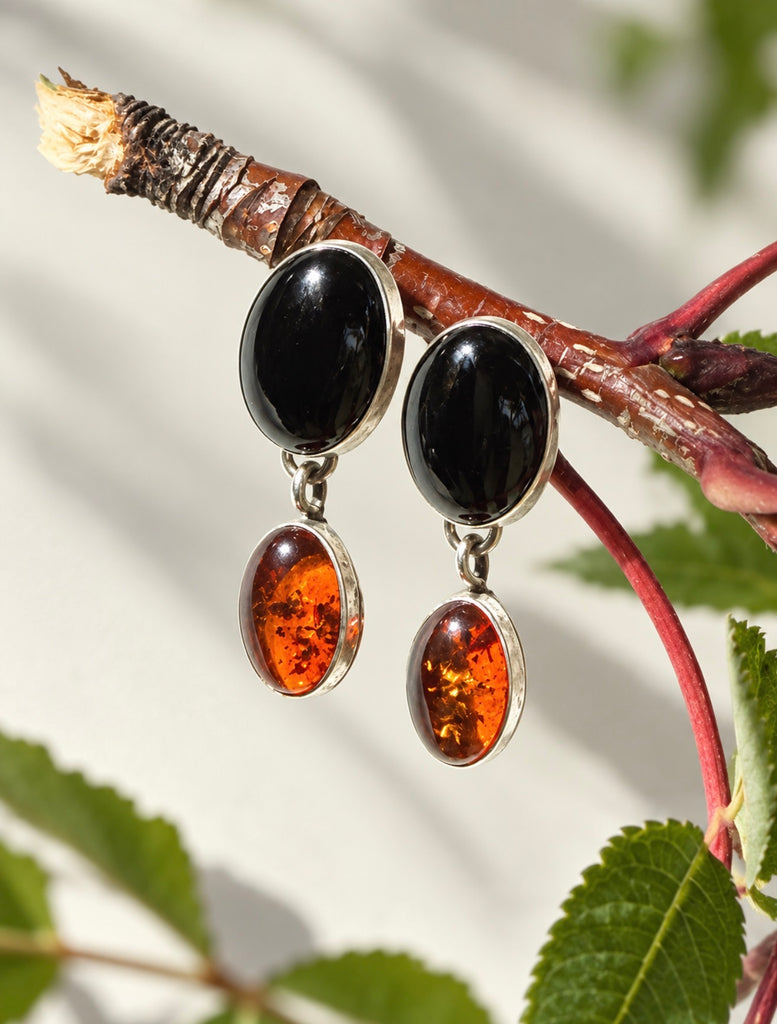 Vintage amber and black onyx sterling silver drop earrings displayed with botanical leaves