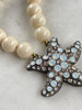 Close-up of Heidi Daus bronze tone starfish pendant with opaline blue clear and shimmering Swarovski crystals