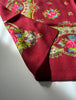 Close-up of burgundy wool scarf with bright pink roses and green floral border