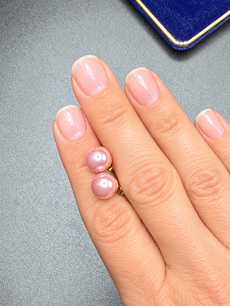 Vintage blush pink faux pearl stud earrings with gold-tone settings worn on hand