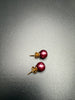 Pair of dark raspberry pink faux pearl stud earrings showing round pearl fronts