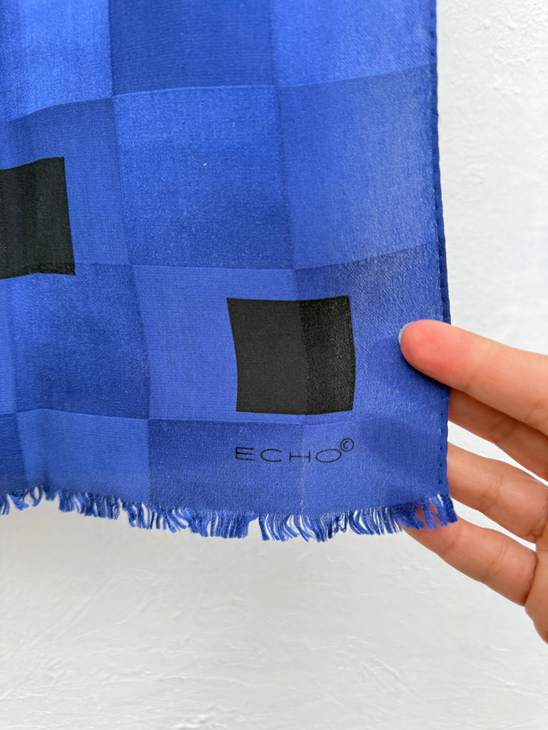 Close-up of vintage Echo silk scarf showing cobalt blue black geometric squares and fringe. 