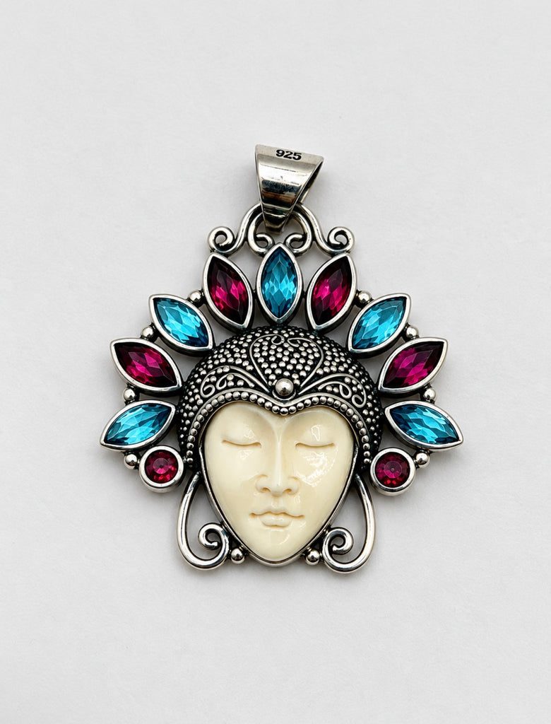 Front of ornate Balinese 925 silver pendant with carved cream face and alternating red and blue gemstones