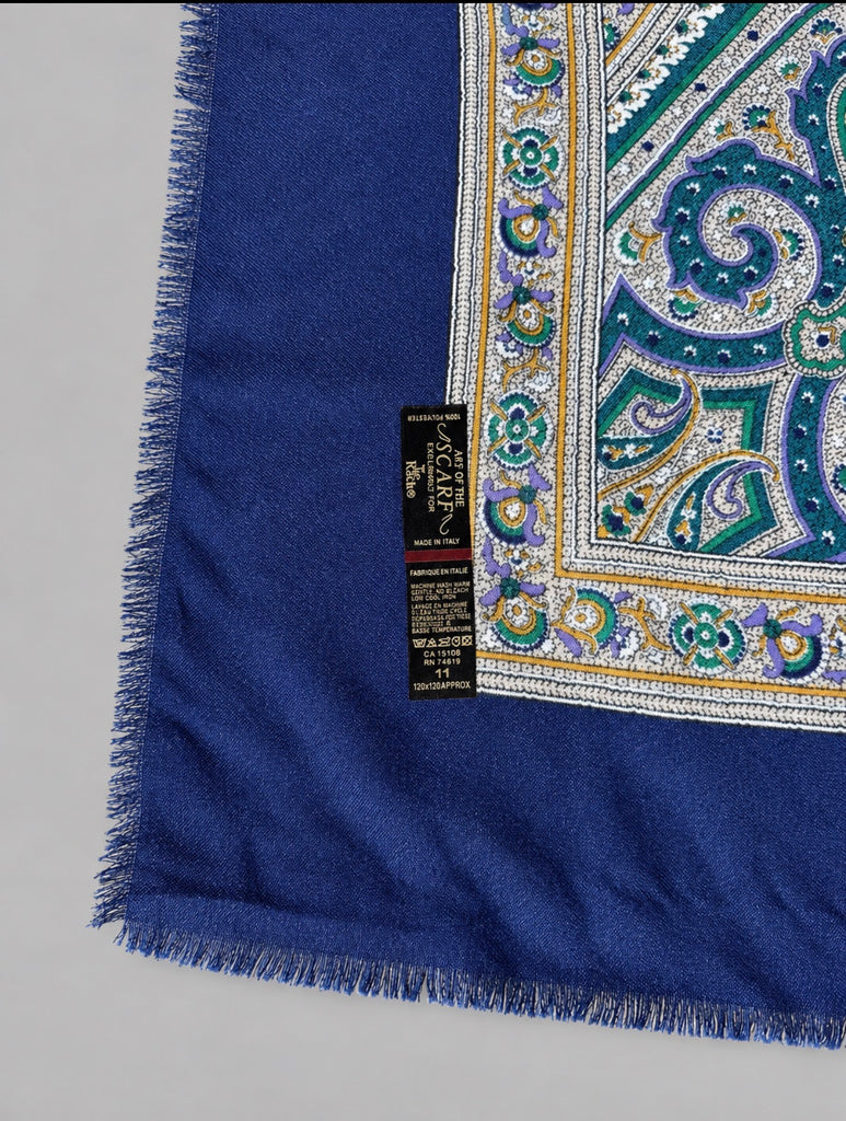 Close-up of ornate teal cream and blue paisley medallion pattern and "art of the scarf, made in italy" tag