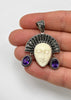 Vintage Balinese goddess pendant shown in hand with carved face and purple gemstone drops
