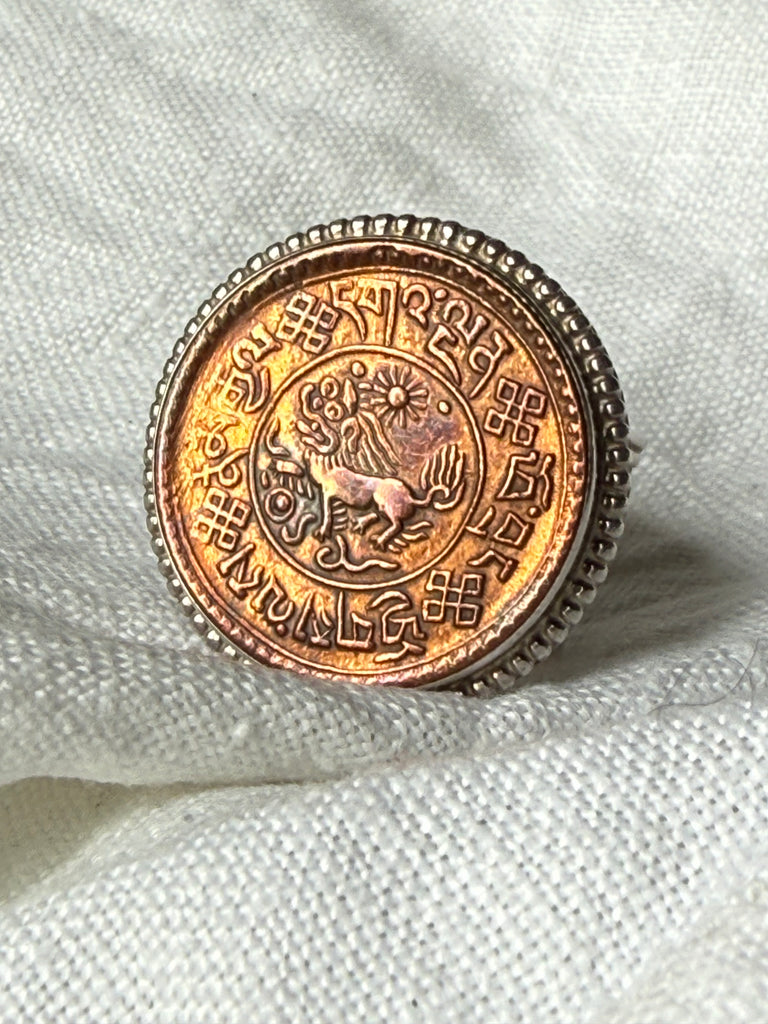 Close-up of copper-toned Nepal coin with detailed lettering and imagery in sterling silver ring