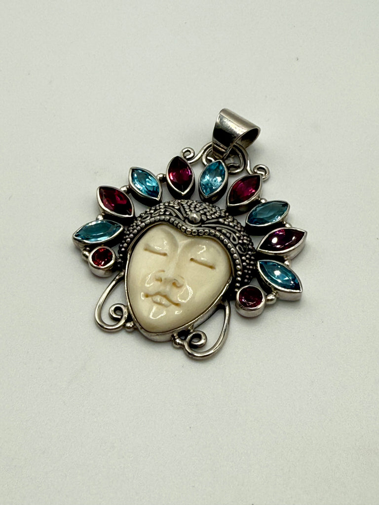 Close-up of Balinese silver pendant showing carved face, granulation and colourful gemstone halo