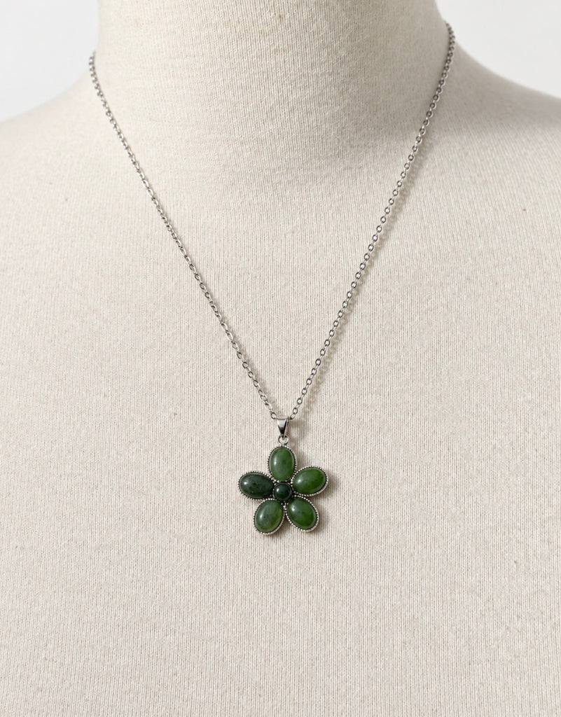 Green jade flower pendant necklace displayed on white jewellery bust