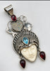 Ornate sterling silver goddess pendant with blue topaz, red garnets and heart-shaped crown design