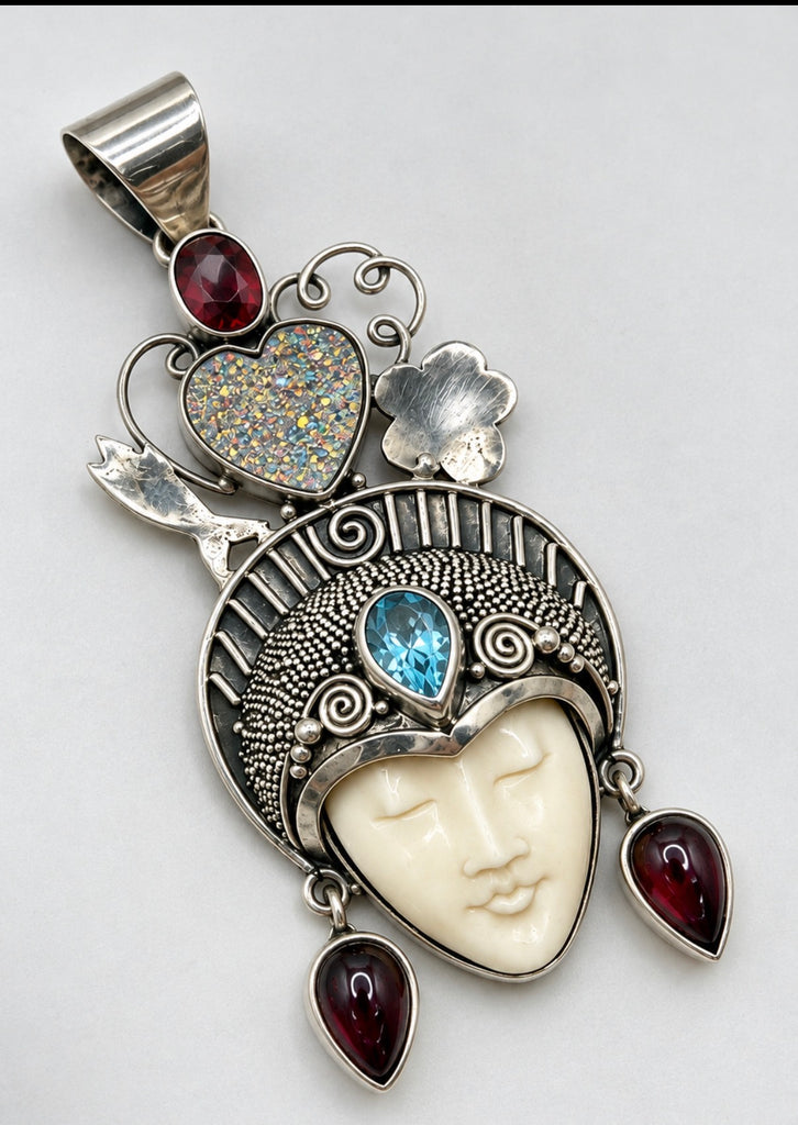 Ornate sterling silver goddess pendant with blue topaz, red garnets and heart-shaped crown design