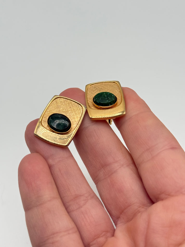 Matching pair of vintage gold-tone cufflinks with polished oval green cabochons held in hand