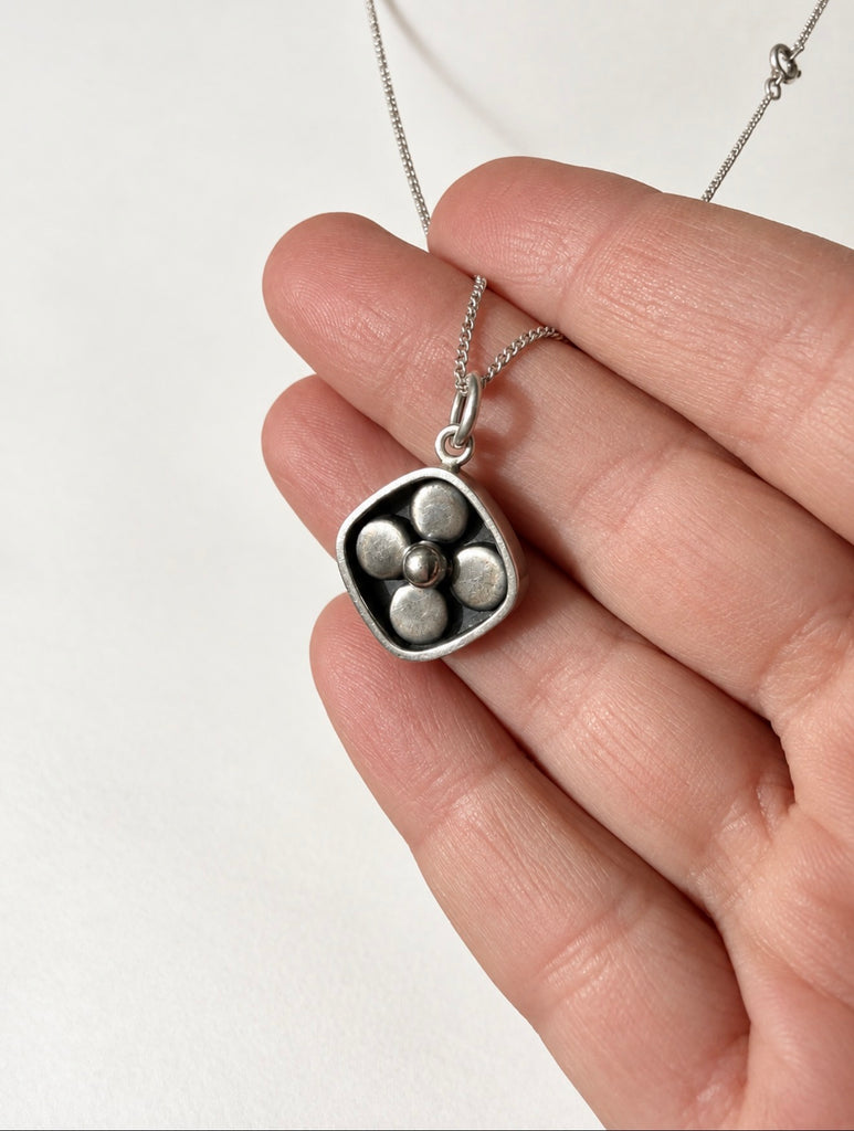 Finnish modernist silver-tone pendant shown in hand for scale