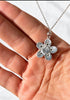 Close-up of reverse side of sterling silver five-petal jade flower pendant held in hand