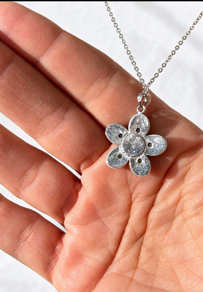 Close-up of reverse side of sterling silver five-petal jade flower pendant held in hand