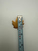 Vintage maple leaf brooch beside measuring tape showing approximately 1.5 inch length